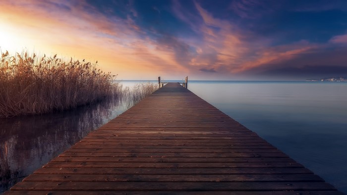 Wooden pier on a lake at sunset with clouds