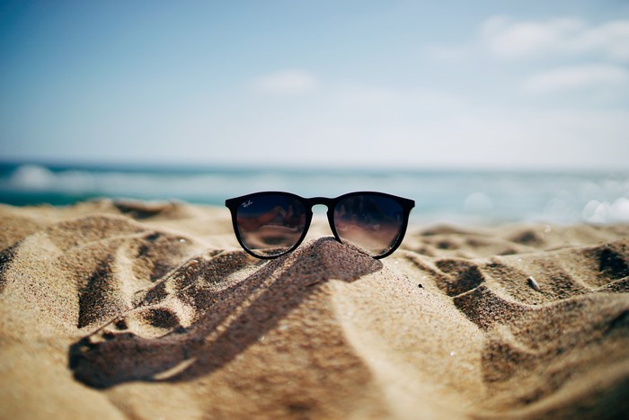 Ray-Ban sunglasses on a sandy beach with the sea