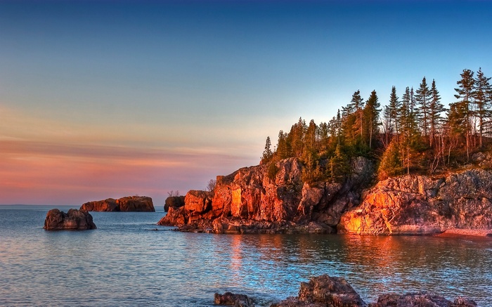 Rocky shoreline with trees at sunset