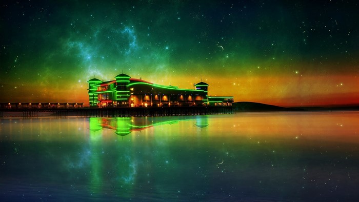 Glowing pier building reflected in water under starry sky