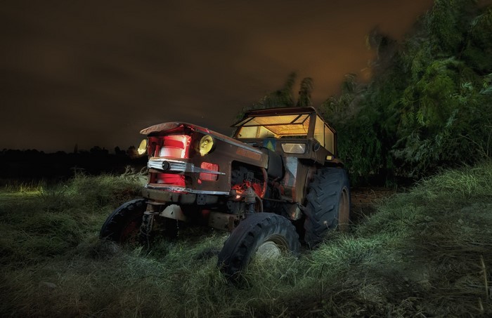 Old tractor in a field at night