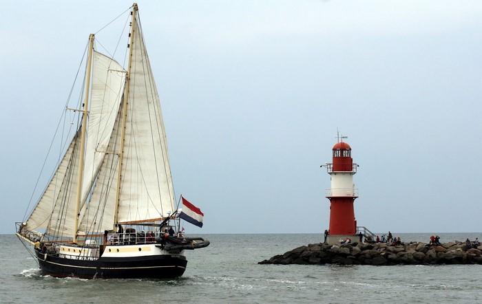 Sailing ship passes a lighthouse in Warnemünde