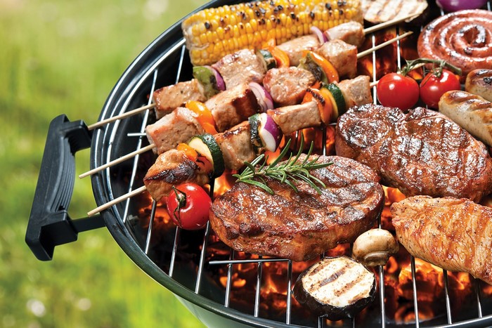 Barbecue grill with steaks, skewers, corn, and sausages