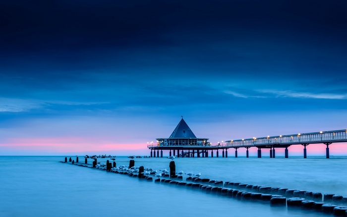 Pier with a building at dusk over the sea
