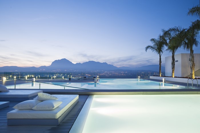 Modern swimming pool with mountains and palm trees at dusk