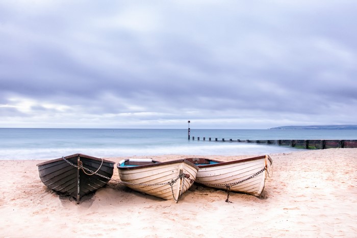 Three boats on a sandy beach in England