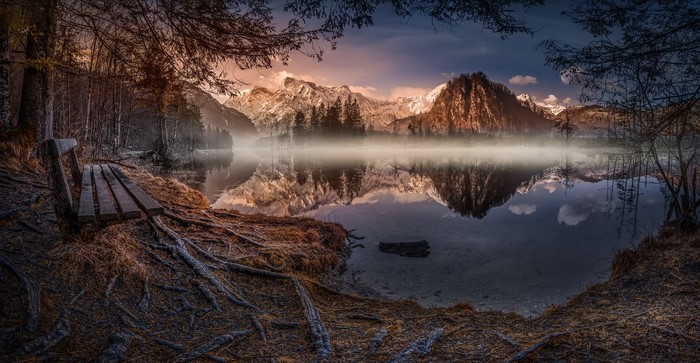 Misty lake with mountains and a bench