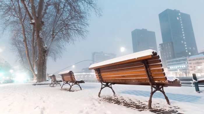 Benches covered in snow by a river in winter