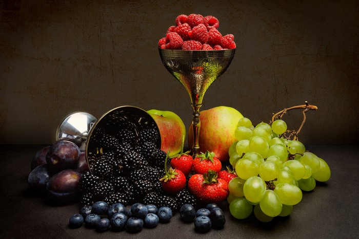 Still life of assorted fruits including raspberries, blackberries, blueberries, strawberries, apples, and grapes