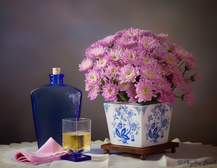 Still life with blue bottle, glass, and pink flowers