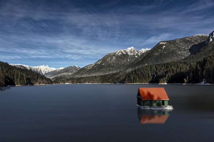 House on a lake with snow-capped mountains