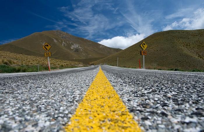 Road through rolling hills with curve warning signs