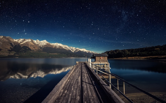Wooden pier and boathouse under starry sky