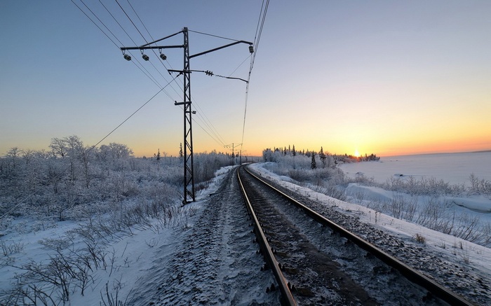 Train tracks in a snowy landscape at sunset