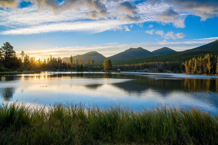 Sunrise over a mountain lake with pine trees