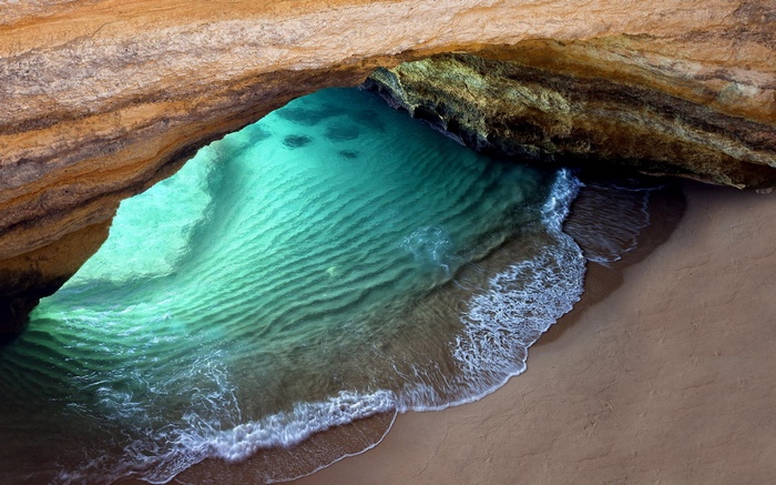 Cave opening with turquoise water and sandy beach