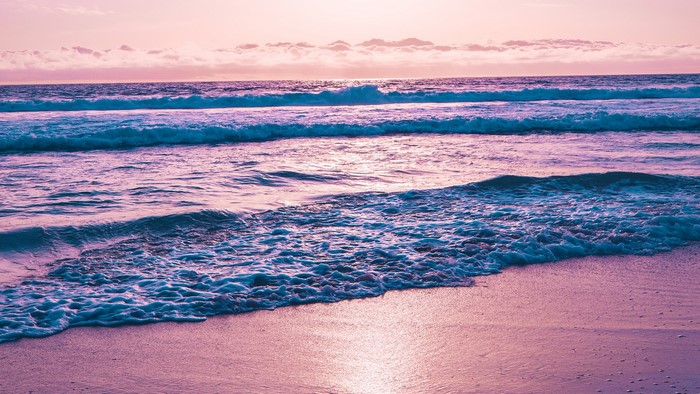 Waves crashing on a beach at sunset
