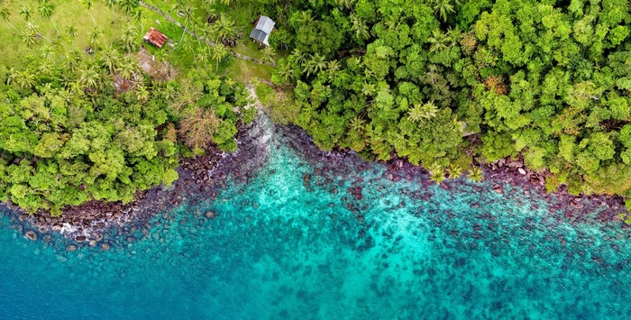 Aerial view of a tropical island coastline with turquoise water
