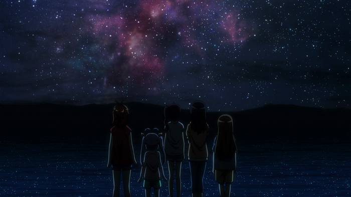 Girls watching a starry night sky over the sea