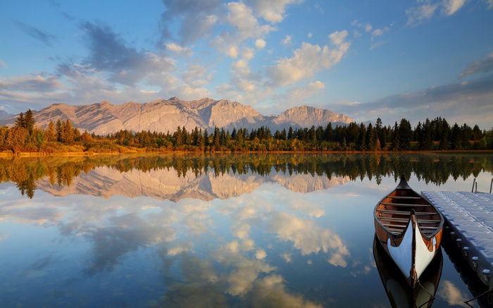 Canoe docked on a calm lake with mountains in the background