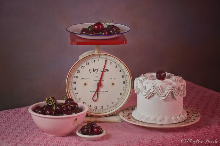 Still life with cherries and cake on a scale