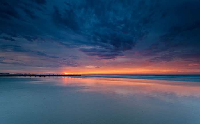 Sunset over the ocean with a pier