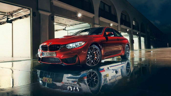 Red BMW M4 on wet ground with garage background