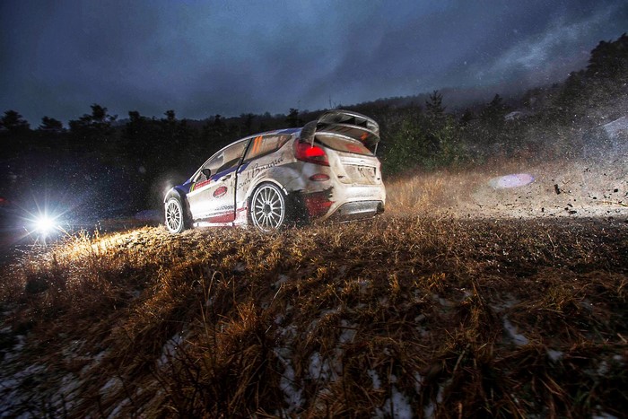Rally car racing on a dirt track at night