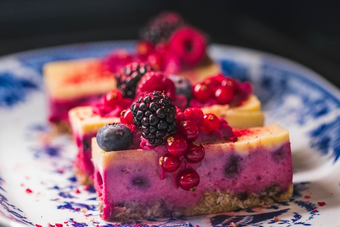 Berry cheesecake slices on a blue and white plate
