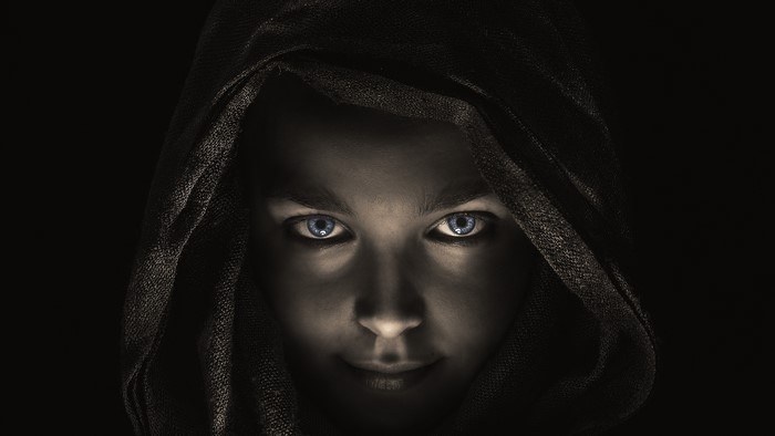 Woman with blue eyes wearing a dark hood