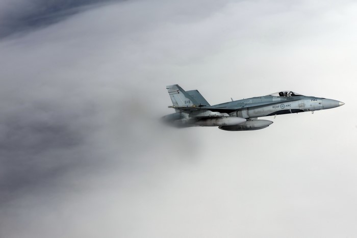 Canadian CF-18 Hornet flying through clouds