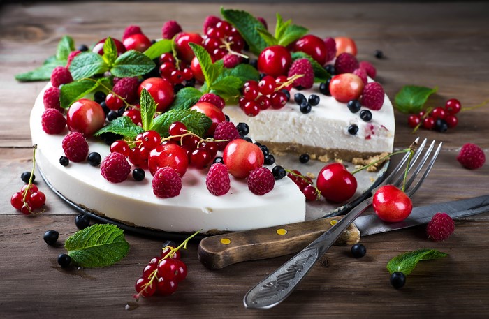 Cheesecake with berries and mint on a wooden surface
