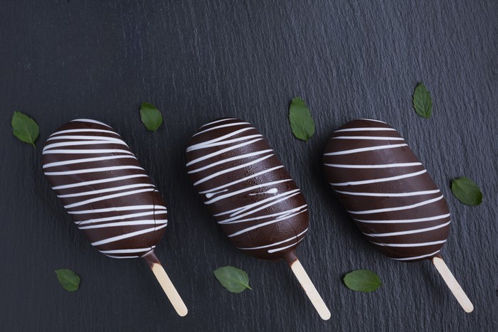 Three chocolate popsicles with white stripes and mint leaves