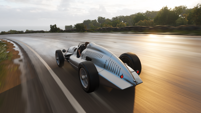 Silver vintage race car driving on a wet road in Forza Horizon 4