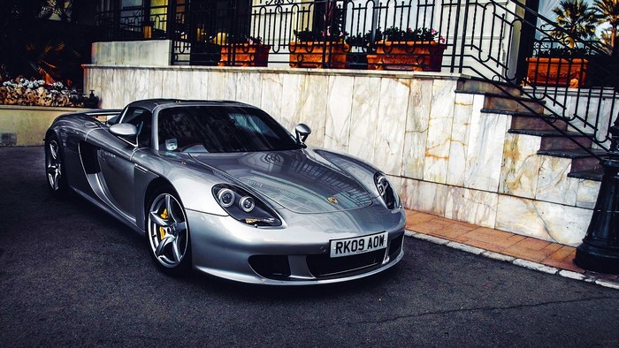 Silver Porsche Carrera GT parked in front of a building