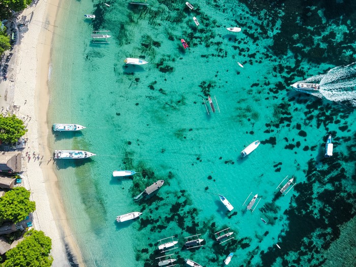 Aerial view of boats on a tropical beach with turquoise water