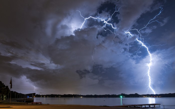 Lightning strikes over a lake at night