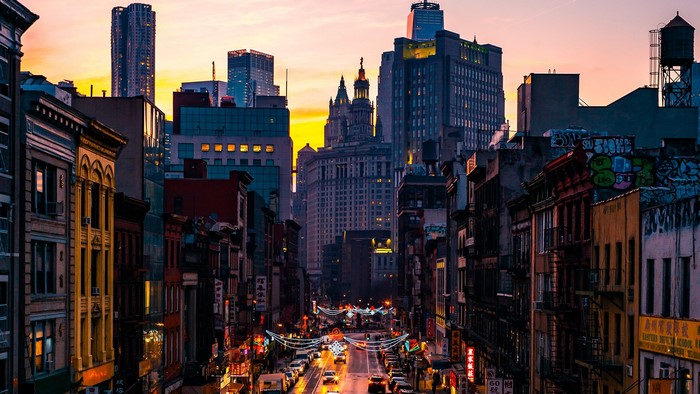 Street view of Manhattan buildings at sunset with lights