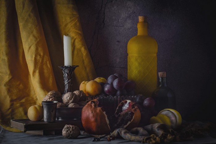 Still life with fruit, nuts, candle, and bottles