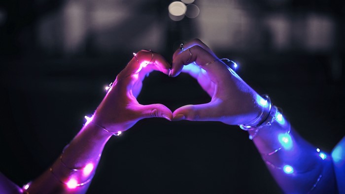 Hands forming a heart shape with LED lights