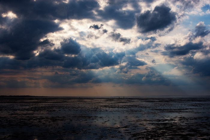 Sun rays breaking through dramatic clouds over a tidal flat
