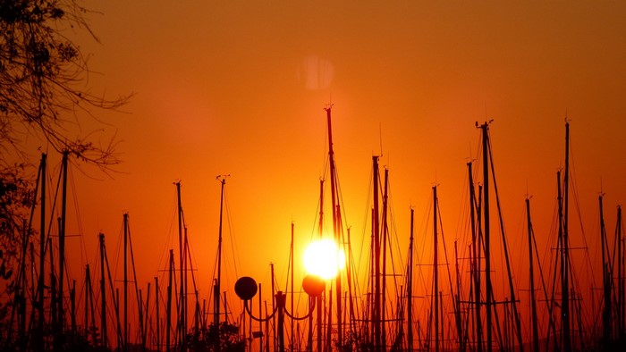 Sunset over a marina with silhouetted sailboats
