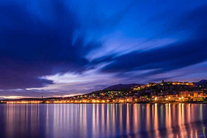 City lights reflecting on the sea at night in Calabria, Italy