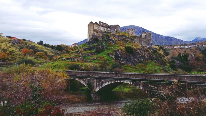 Ruined castle on a hill above a bridge in Calabria, Italy