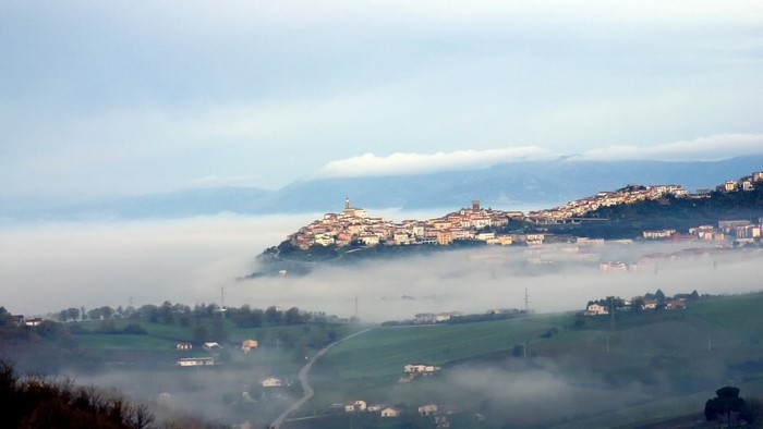 Town on a hill above fog in Calabria, Italy