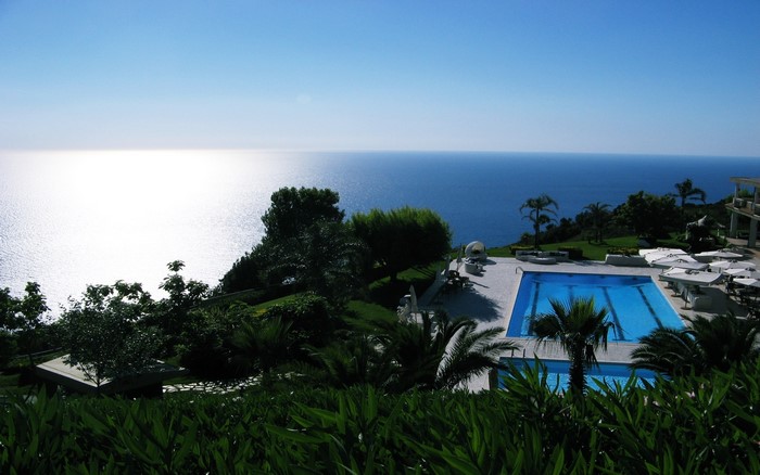 Resort swimming pool overlooking the sea with trees