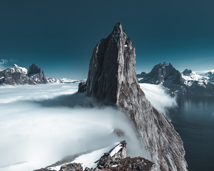 Snowy mountains above clouds and ocean