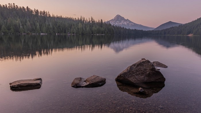 Lake reflection of mountains and forest at sunset