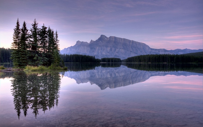 Mountain reflected in a calm lake with pine trees
