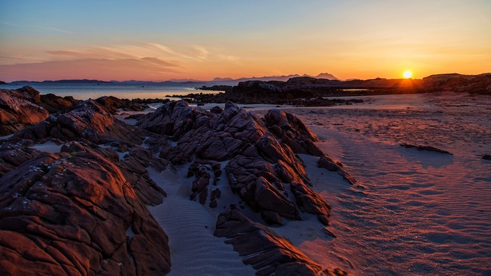 Rocky beach at sunset with distant mountains
